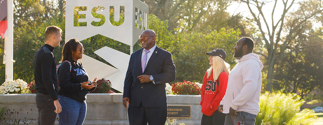 President Kenneth Long standing in front of campus with students