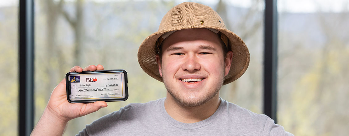 An ESU student holds up a phone showing a photo of a check he won in the PASSHE Startup Challenge
