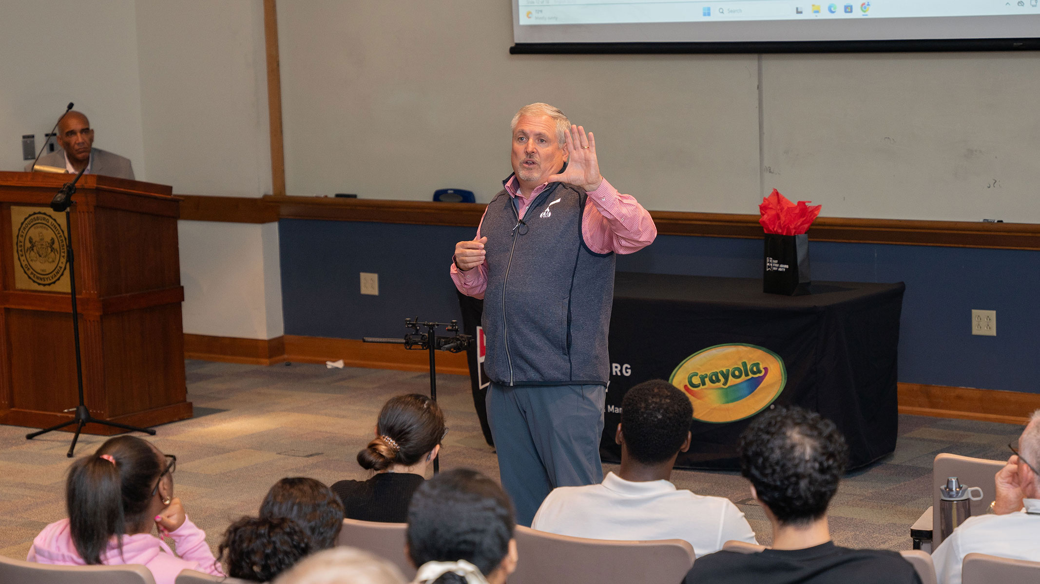 A speaker gesturing as lectures to an audience