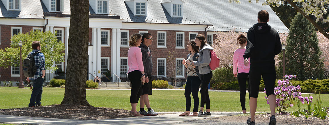 Students talking outside Monroe Hall on a sunny day