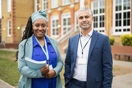 two education leaders standing outside of school building