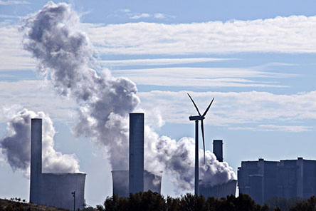 Factories in background with smoke and windmill in foreground