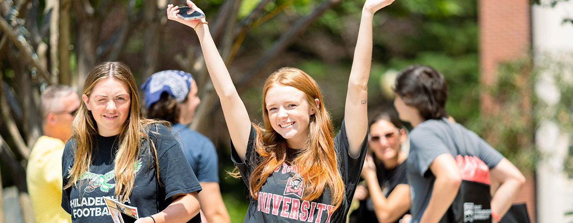 new female student attending orientation and raising her hands above her head and smiling
