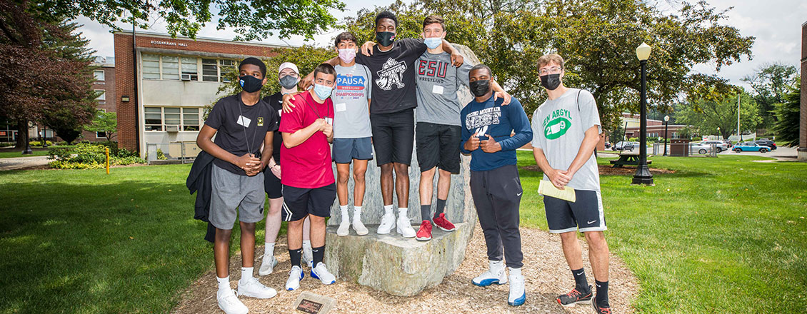 7 male students standing on a rock during orientation