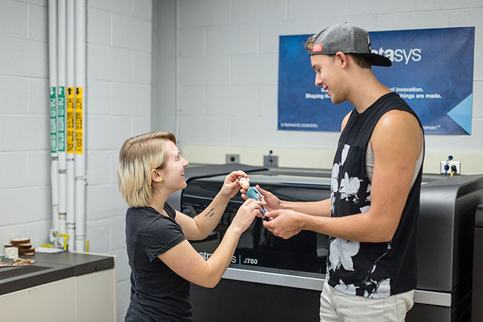 Students examining something printed by the 3D Printer