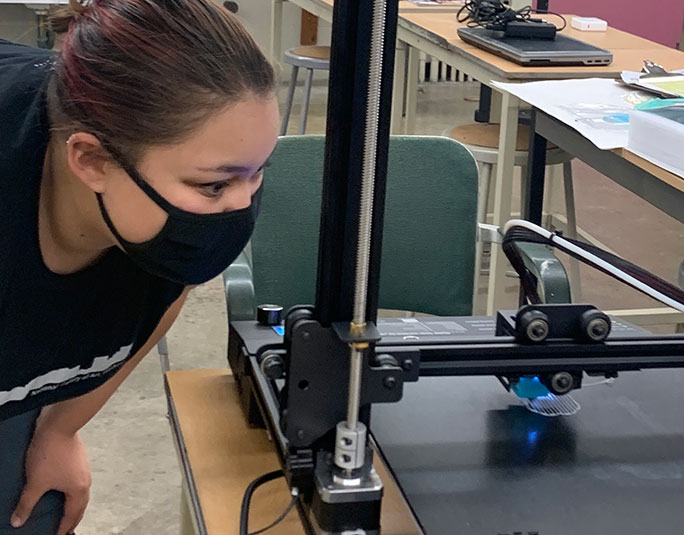 A student watching a 3d printer at work