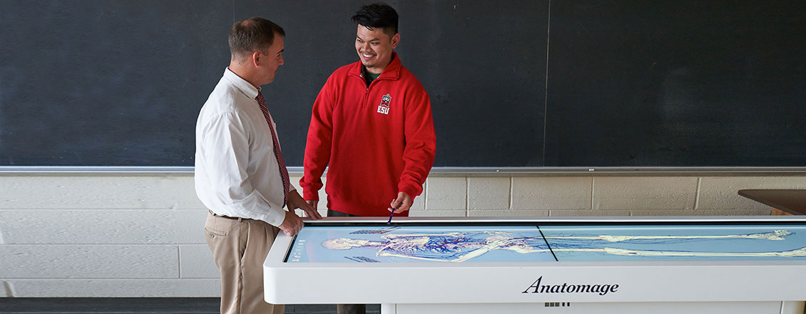 Dr. Rozea speaking with male student at Anatomage table