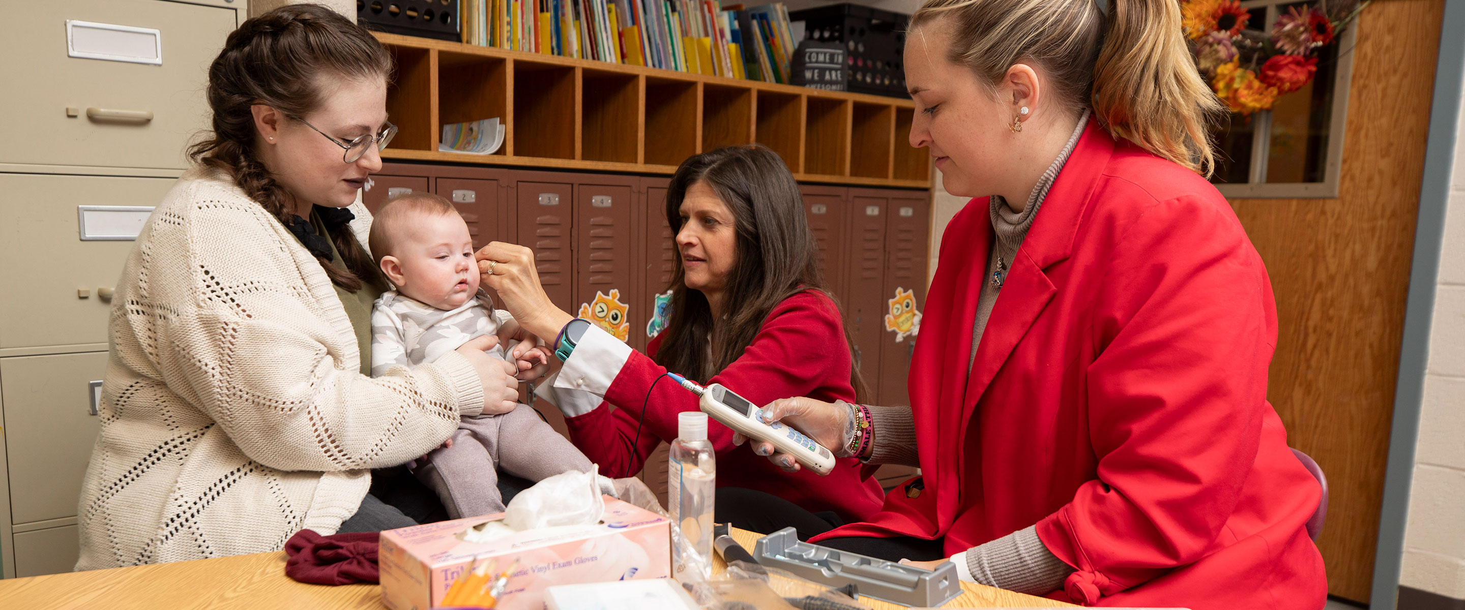 professor adding hearing aid to infant