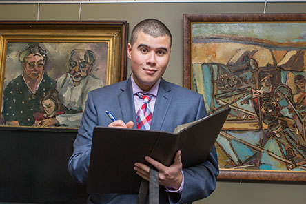 male student holding note pad while speaking to group