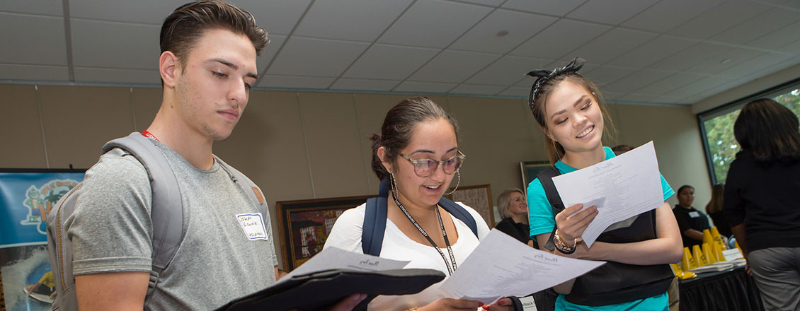 3 students reading internship application at career fair