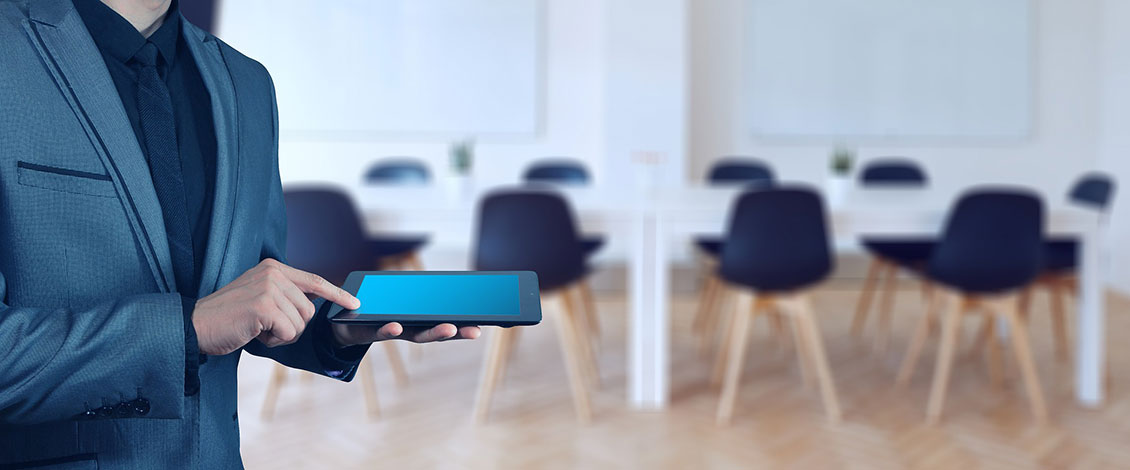 man holding tablet in front of classroom