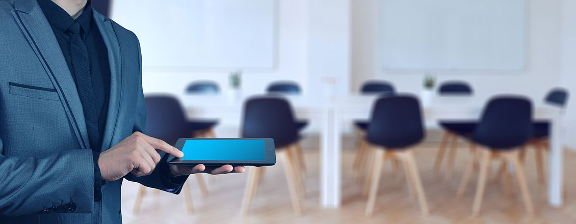 man holding tablet in front of classroom