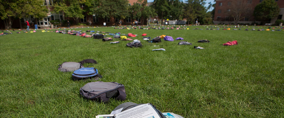 Backpacks arranged on the grass for a "Send Silence Packing" event