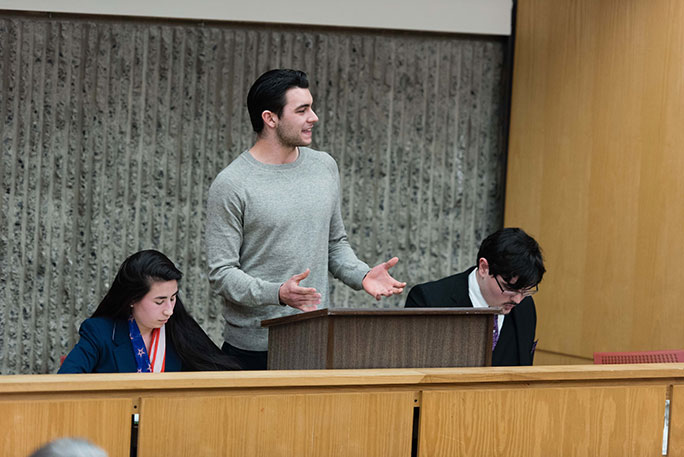 A student speaking during a debate, with others listening