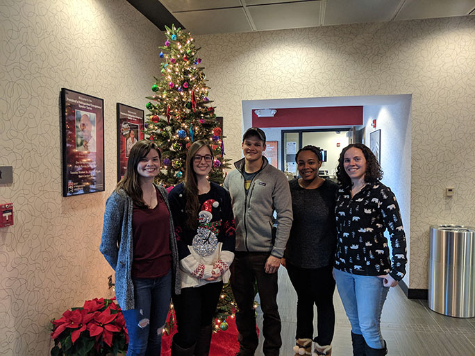 Fall 2018 interns standing by a Christmas tree