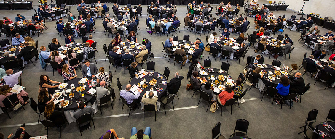 Over a dozen tables filled with attendees at the Economic Outlook Summit