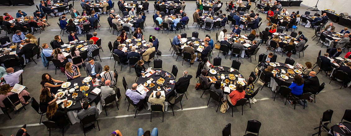 Over a dozen tables filled with attendees at the Economic Outlook Summit