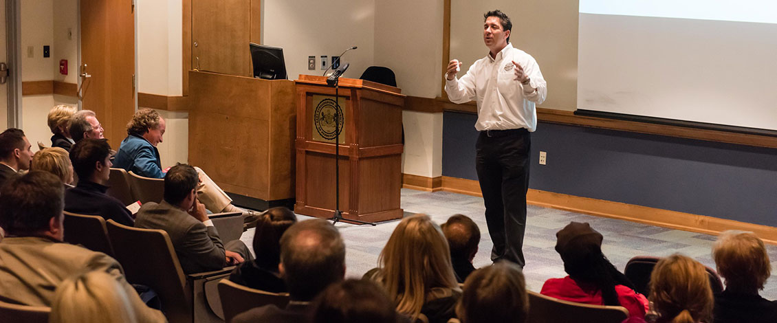 A speaker gesturing as lectures to an audience