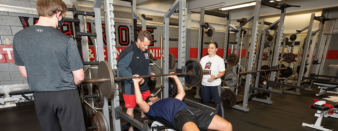 student doing bench press in gym