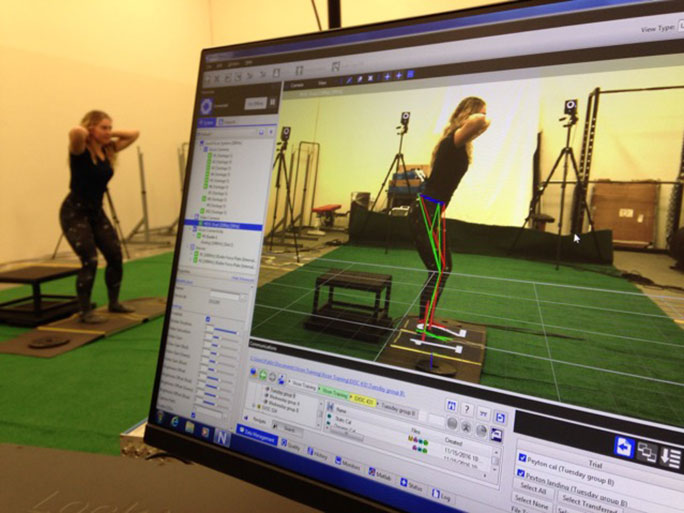 A women does an exercise while a computer monitor shows an analysis of her movements