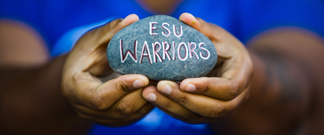 female student holding painted rock that says ESU Warriors