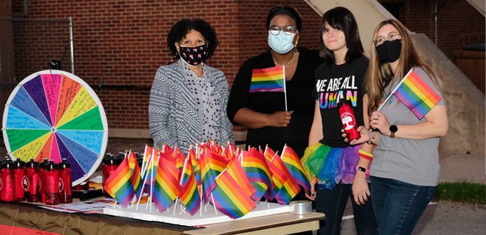 A large group of people gathered together, some holdling LGBTQ+ flags