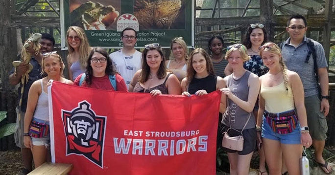 Students and RSM faculty in a wildlife restoration location, holding up an ESU banner