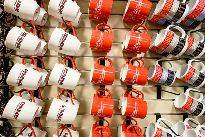 Three styles of ESU-branded mugs hanging on a wall