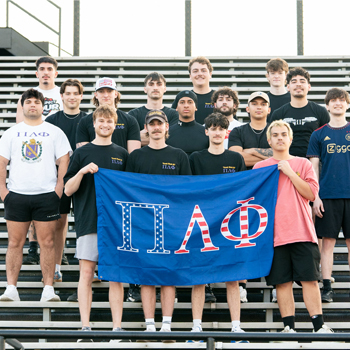 Members of Pi Lambda Phi holding their chapter's flag