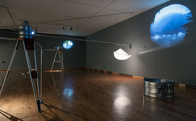 Margaret Cogswell - comprised of video projected from three surveyor’s transits; video projected onto the floor of a stock tank; and a bucket of light which moves almost imperceptibly slowly 50 feet diagonally across the gallery space.