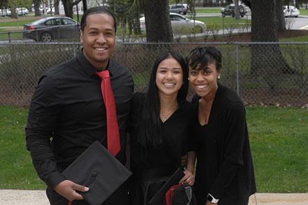 Three students smiling, dressed for the ALANI Ceremony