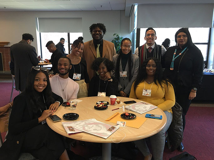 Students wearing conference badges, smiling around a table