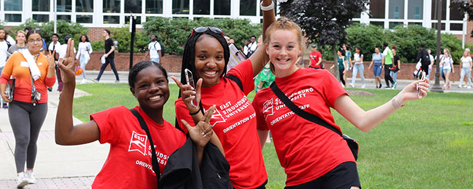 three student orientation leaders posing with a group of students following