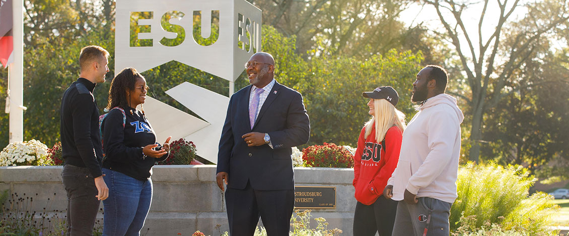 President Kenneth Long standing in front of campus with students