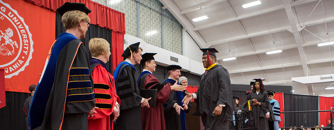 graduate student shaking hands on stage during commencement