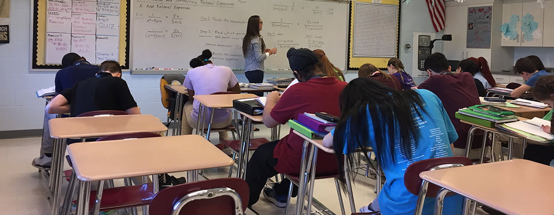 elementary students sitting at desk taking notes during class
