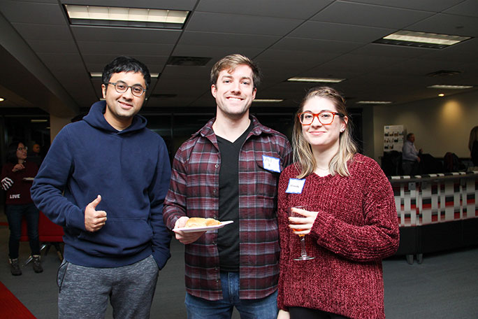 two male students and one female student standing with name tags on