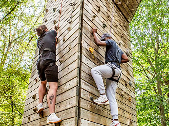 a male and female student climbing rock wall