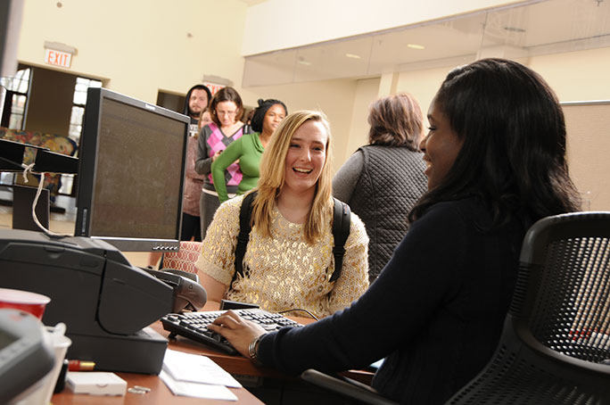 A staff member typing and assisting a student