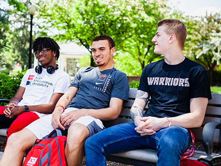 3 male students siting on bench in summer