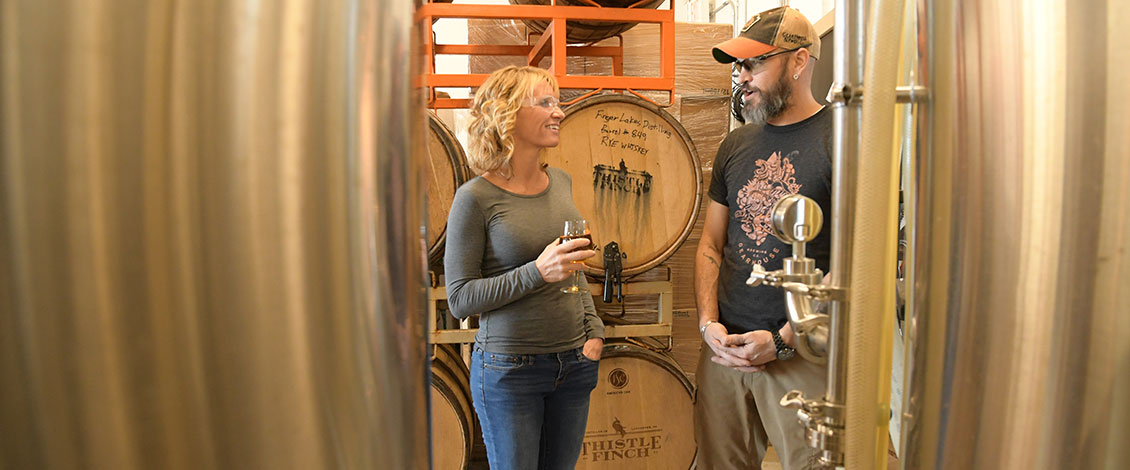 Alison Feeney and a man standing near several barrels of liquor