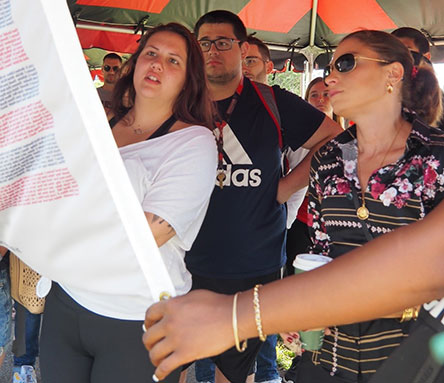 Students holding up and reading a flag with many names writen on it