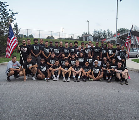 The wrestling team sitting for a photo, carrying two American flags