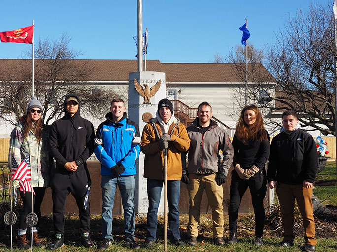 a group of people standing in front of a veterans' memorial